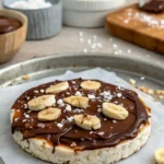 Giant peanut butter rice cake topped with banana, chocolate, and sea salt.